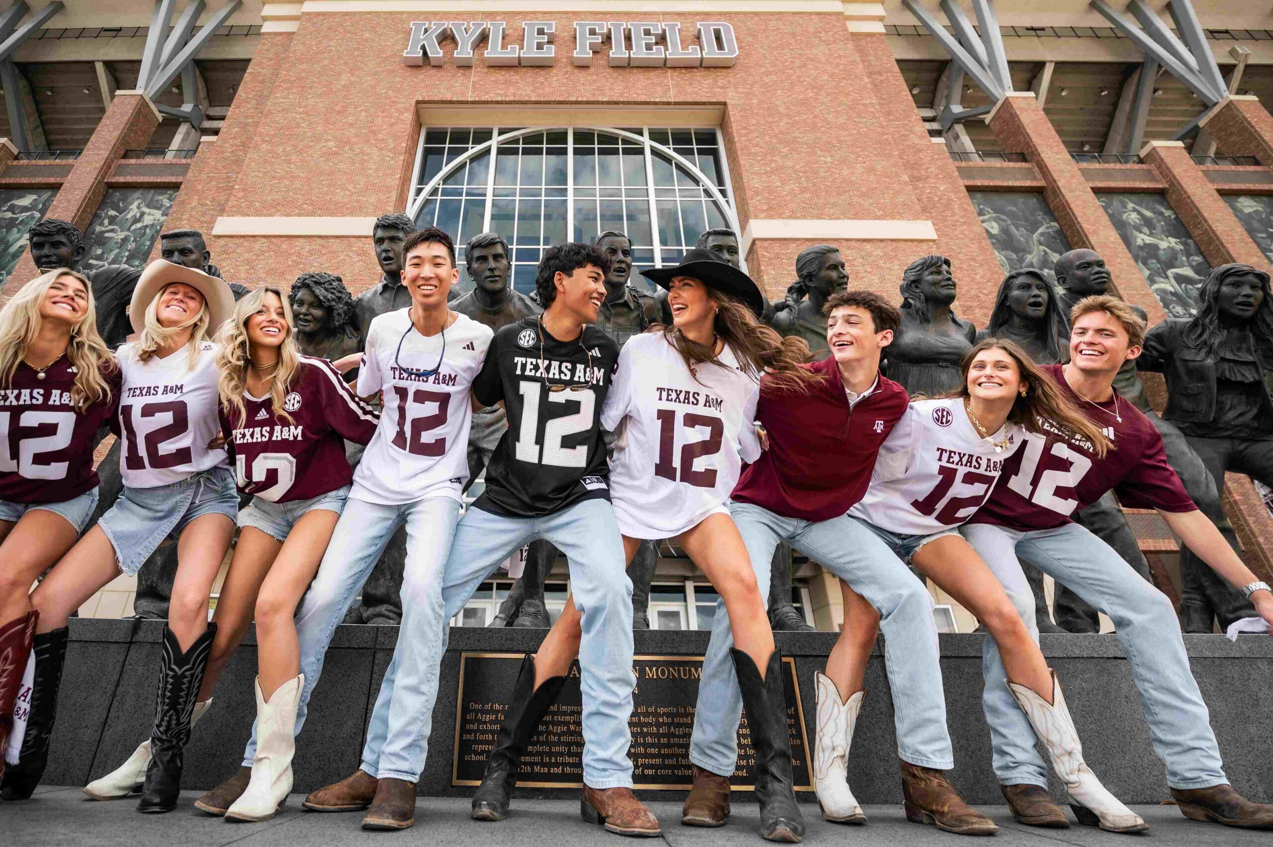 students posing at kyle field monument near honcho in college station tx scaled